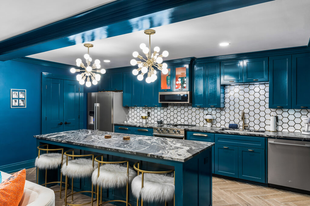 Colorful kitchen with high gloss teal cabinets and center island. Mid century light pendants